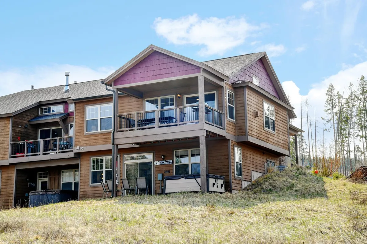 This image captures the exterior of the property, featuring a welcoming balcony framed by large windows and wooden siding. The balcony hints at relaxation and luxury, with scenic mountain views visible in the background. The inviting mood suggests a space designed for comfort and leisure, seamlessly connecting the indoors with the breathtaking outdoor environment.