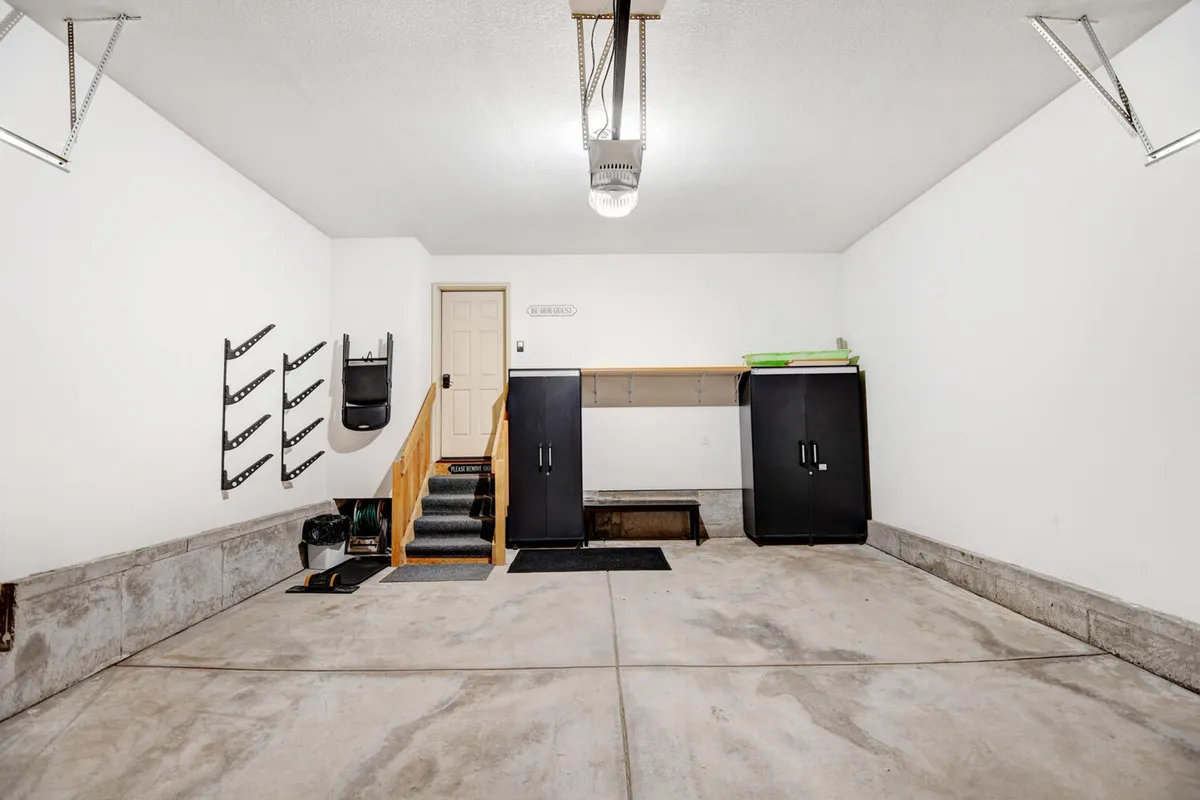 A practical interior garage space featuring shelving units and storage for tools, along with visible stairs and cabinetry. The scene hints at an organized area well-suited for storing adventure gear like skis, snowboards, and bikes.