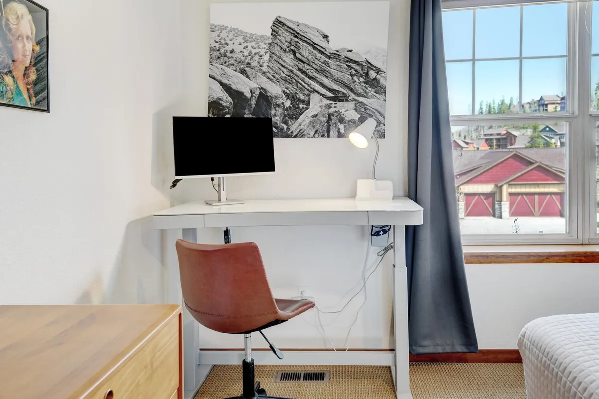 A focused, serene workspace with a desk, computer monitor, lamp, and window view, subtly decorated with inspiring artwork. Natural light streams in, creating an inviting yet productive atmosphere.