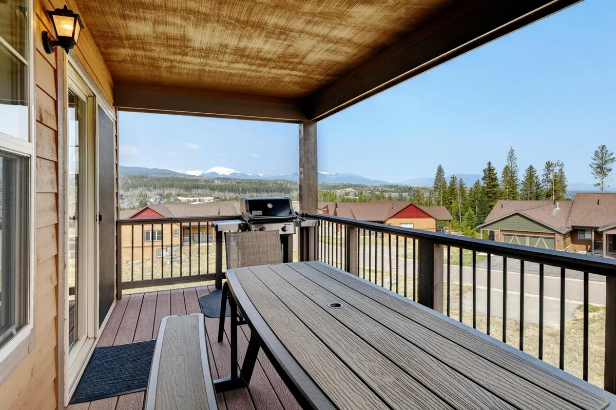 An inviting outdoor dining area equipped with a grill, table, and chairs. The scene features a beautiful view of the mountains in the background, perfectly capturing the essence of al fresco dining and social gatherings.